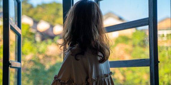 Person med ryggen til ser ud gennem et åbent vindue